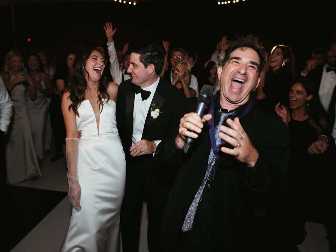 Lead singer of Society Hill on the dance floor with a bride and groom